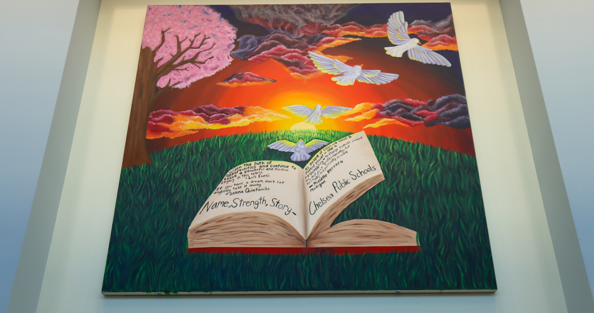 A mural hanging in Chelsea High School's library that is an open book with quotes in an open field.